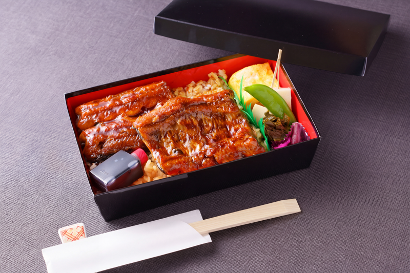 照りのあるうなぎをご飯にのせたテイクアウト弁当